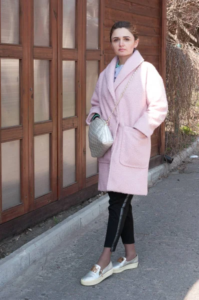 분홍색 코트와 바지에 지갑을 여자는 카메라를보고 — 스톡 사진
