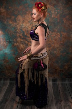 Kırmızı çiçek çemberiyle dans eden güzel bir kadının el ele tutuşup deniz mavisi ve turuncu arkaplan önünde el ele tutuşması.