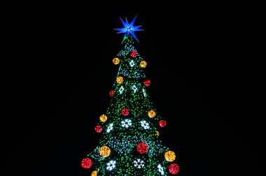 Çok renkli ışıkları, topları ve siyah üzerine izole edilmiş mavi yıldızlı Noel ağacının tepesinde. 