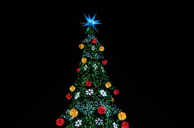 Rengarenk ışıkları, topları ve siyah üzerine izole edilmiş yıldızlı Noel ağacının tepesinde. 