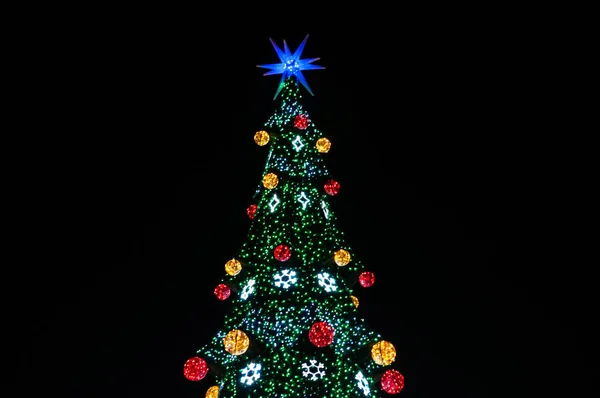 複数の色のライト ボールと黒に隔離された青い星を持つお祝いのクリスマスツリーの上 — ストック写真