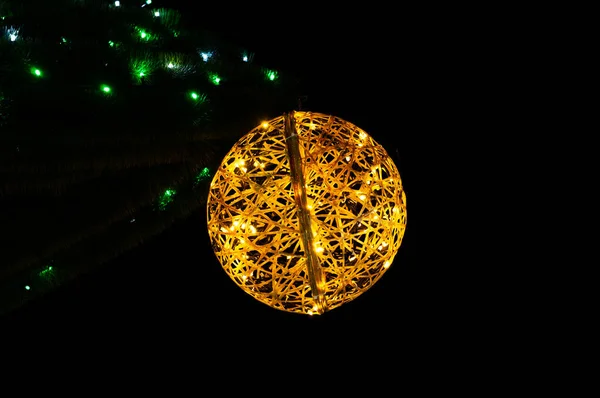 コピースペース付き黒の背景に緑のライトの近くの光沢のある黄色のクリスマスボールの低角度ビュー — ストック写真