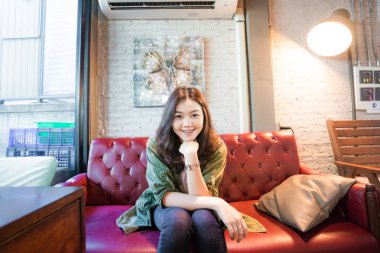 Güzel Asyalı kadınlar kafede vintage kanepede oturan sıcak kahve içme