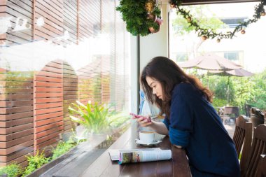 Güzel Asyalı kadınlar kafede vintage kanepede oturan sıcak kahve içme