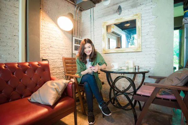 카페에서 빈티지 소파에 따뜻한 커피를 마시는 아시아 — 스톡 사진