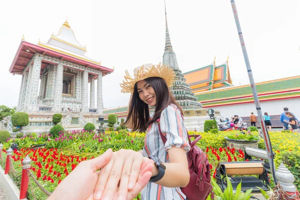 Asian tourist women leading man hand to travel in old buddha temple, Bangkok Thailand