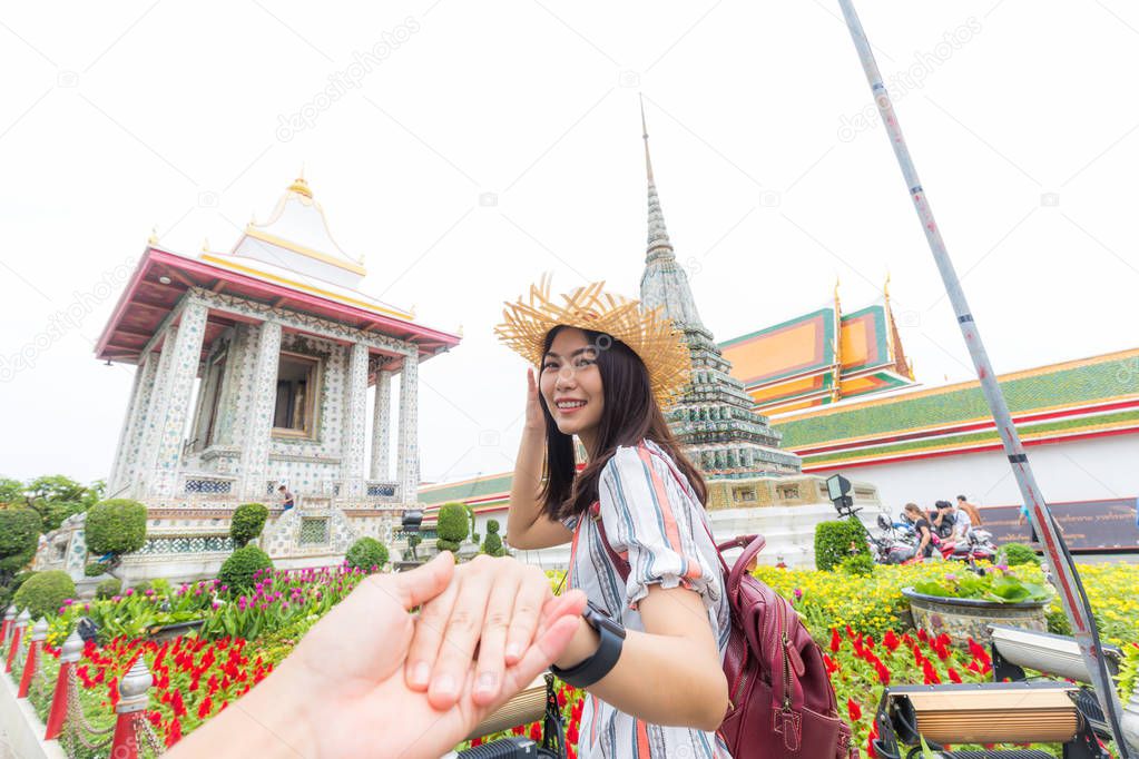 Tourist asian women leading boyfriend hand to travel in buddha temple of dawn, Bangkok Thailand