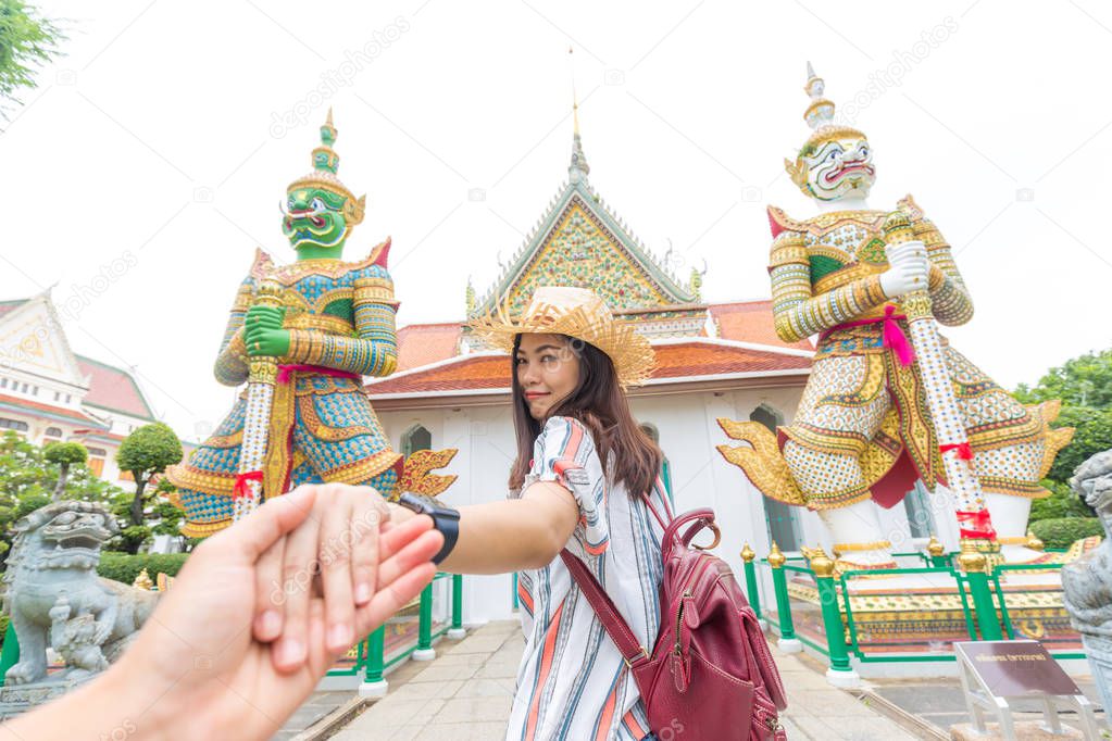 Tourist asian women leading boyfriend hand to travel in buddha temple of dawn, Bangkok Thailand