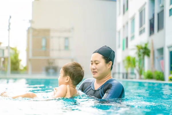 Funny boy enjoy swimming with mother in pool, People water sport