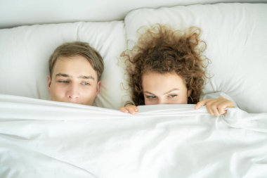Komik beyaz evli çift yatakta yatarken görünümü top ve yarım yüz gülümseyen gizle