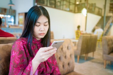 Divan grubu smartphone arka plan kullanarak kafede oturan kadın