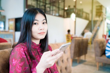 Divan grubu smartphone arka plan kullanarak kafede oturan kadın