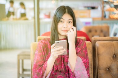 Divan grubu smartphone arka plan kullanarak kafede oturan kadın