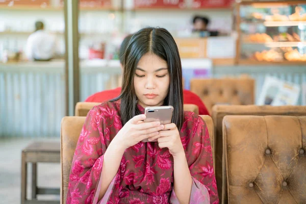 Divan grubu smartphone arka plan kullanarak kafede oturan kadın