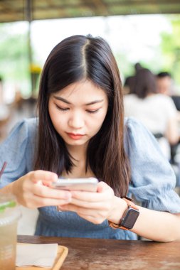 Genç güzel akıllı cep telefonu finans, iş, online alışveriş için kafede kullanan kadın internet bankacılığı. bulanık insanlar arka plan