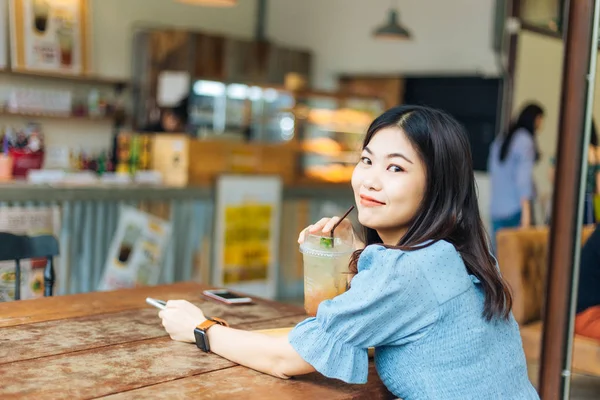 商业亚洲妇女与冰饮料在咖啡店模糊的人背景 — 图库照片