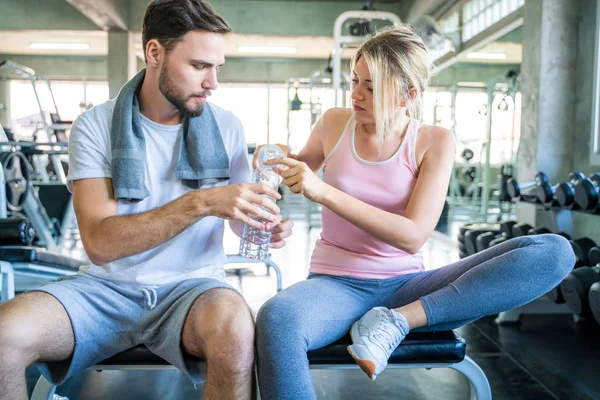 Athletic young couple relax and drinking water after work out in gym, Caucasian sport people