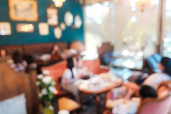 Blurred group of people drink coffee sitting in cafe with bokeh