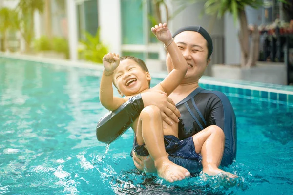 Funny boy enjoy swimming with mother in pool
