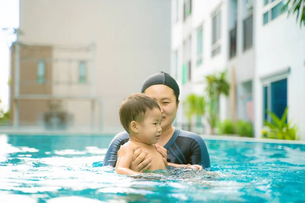 Funny boy enjoy swimming with mother in pool