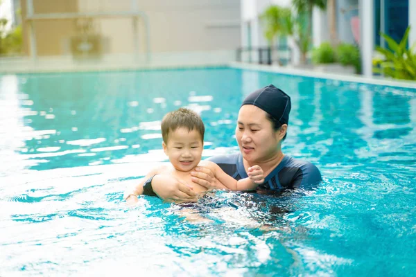 Engraçado menino gosta de nadar com a mãe na piscina — Fotografia de Stock