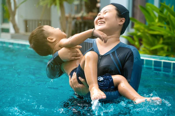 Funny boy enjoy swimming with mother in pool