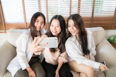 Gülümseyen Asyalı iş kadınları selfie çekiyorlar.