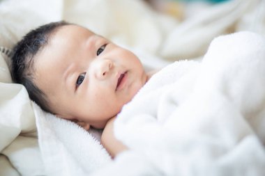 Beyaz battaniye üzerinde yatan Asyalı erkek bebek sabah uyanmak