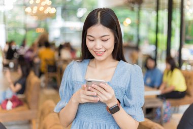 Kahve dükkanında akıllı telefon internet tarayıcısı kullanan güzel kadınlar