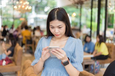 Kahve dükkanında akıllı telefon internet tarayıcısı kullanan güzel kadınlar