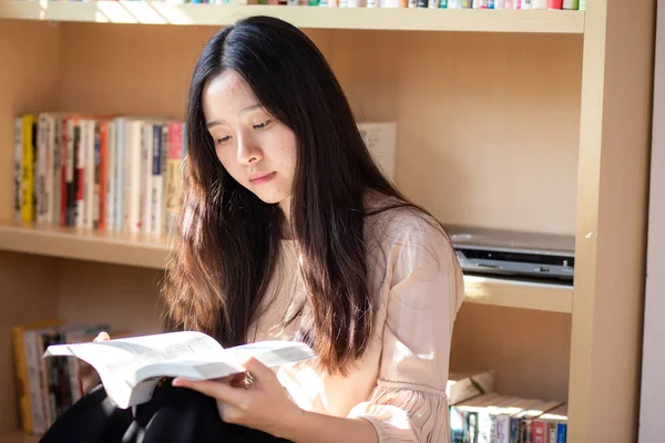 Vacker asiatisk tjej röd en bok som sitter i rummet — Stockfoto