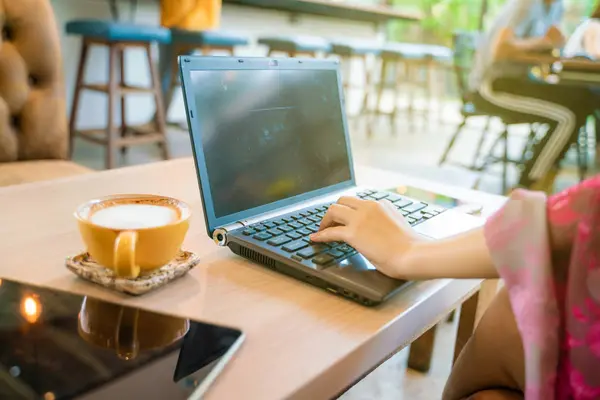 Kadınlar bir fincan latte kahve ile dizüstü bilgisayarda el yazma — Stok fotoğraf