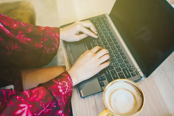 Kadınlar bir fincan latte kahve ile dizüstü bilgisayarda el yazma — Stok fotoğraf