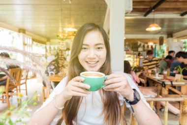 Gülümseyen asya güzel kadınlar sıcak latte kahve içme