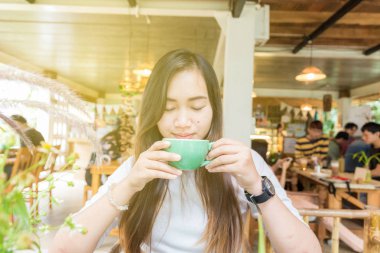 Gülümseyen asya güzel kadınlar sıcak latte kahve içme