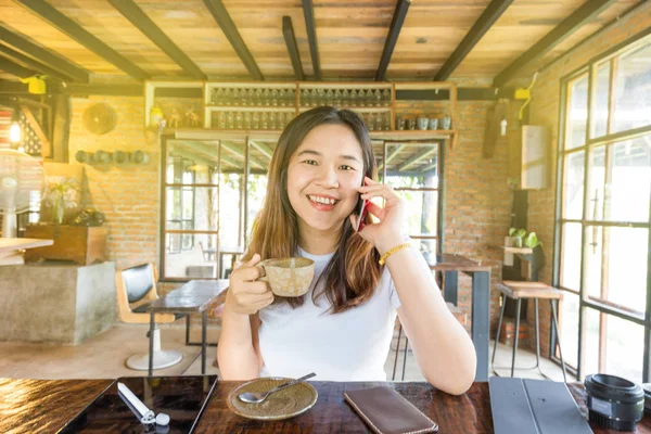 Beautiful asian business women use smartphone sitting in cafe — Stock Photo, Image