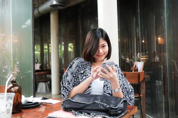 Negócios mulheres asiáticas usando smartphone sentado no café — Fotografia de Stock