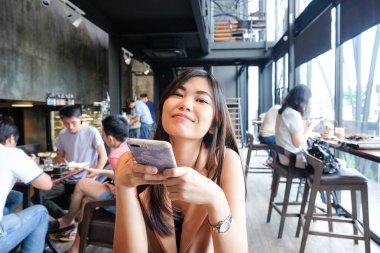 Güzel Asya Smiling kadınlar kullanarak Smartphone içinde kahve dükkanı