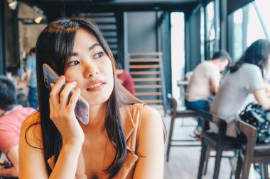 Güzel Asya Smiling kadınlar kullanarak Smartphone içinde kahve dükkanı