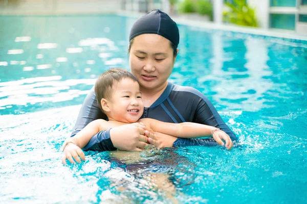 Criança menino aprender a nadar com a mãe na piscina — Fotografia de Stock