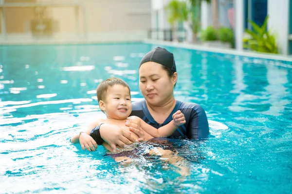 Criança menino aprender a nadar com a mãe na piscina — Fotografia de Stock