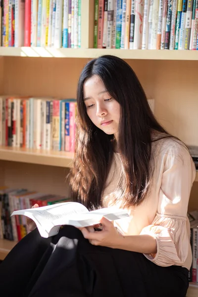 Porträtt av unga vackra asiatiska kvinnor med bok på hyllan att — Stockfoto