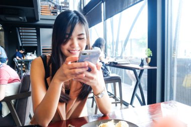 Kahve dükkanında samrtphone kullanan asyalı kadınlar