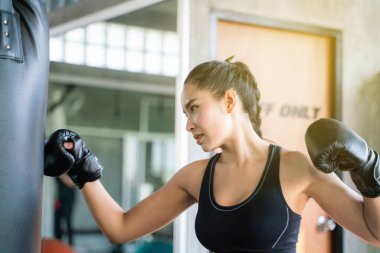 Genç Asyalı kadınlar kum torbası ile boks eğitimi yapıyor