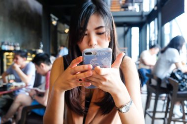 Kahve dükkanında samrtphone kullanan asyalı kadınlar