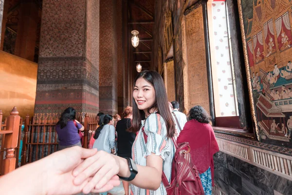 Mooie toeristische vrouwen met rugzak leidende man hand reizen in — Stockfoto