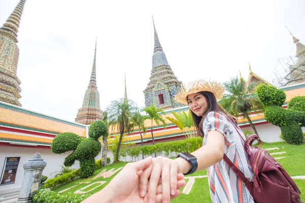 Mooie toeristische vrouwen met rugzak leidende man hand reizen in — Stockfoto