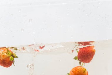 Beyaz arka planda suda taze çilek sıçraması