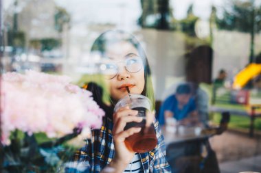 Güzel Asyalı gözlüklü kadınlar kafede kahve içiyorlar.