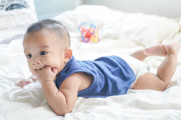 Adorável bebê menino chupando o dedo deitado na cama — Fotografia de Stock